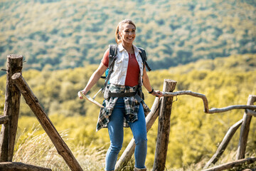 Fototapeta premium The girl researcher walks in nature, carries a backpack and a map in her hands, stands and smiles