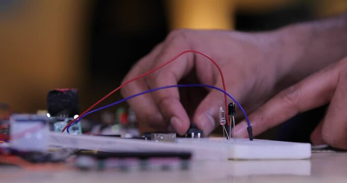 Electronic components in the breadboard and a hand working on a breadboard