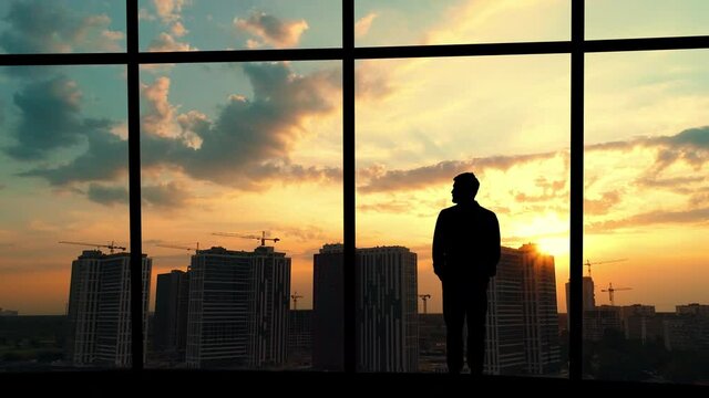 The man is standing in the office on the building background