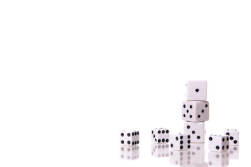 Scattered white dice and Stack of three white dice are reflected on table surface isolated on white background copy space