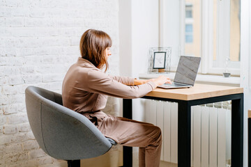 The correct position posture when working at the computer. A woman sits at a table with a laptop...