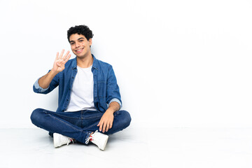 Venezuelan man sitting on the floor happy and counting four with fingers