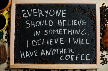 Everyone  should believe in something. I believe i will have another coffee. Words on blackboard flat lay.