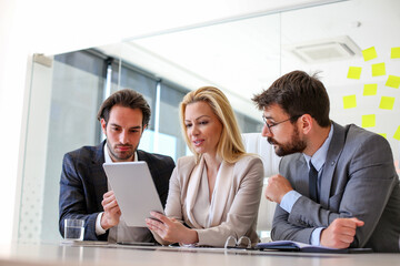 Two colleagues talk to their boss who shows them new information on a notepad