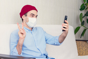 Guy in a medical mask sits at home on self-isolation, a man takes a selfie, a portrait, tinted
