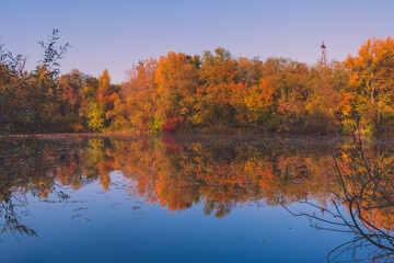 Colorful autumnal photo of a small lake, autumnal small lake with colorful trees in the background, reflections