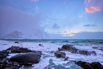 Beach of Norwegian sea on rocky coast in fjord on sunset in winter. Vareid beach, Lofoten islands, Norway