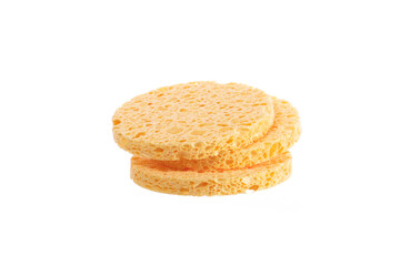 Three stacked Beige round cosmetic sponge pads for face make-up cleaning isolated on white background. Skin care, pure beauty concept
