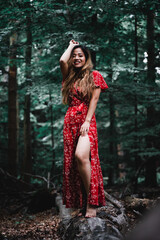 Beautiful Asian woman in red dress standing in a forest