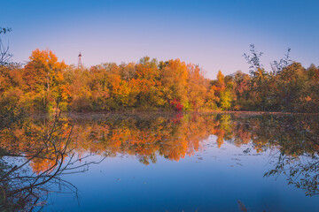 Obraz premium Colorful autumnal photo of a small lake, autumnal small lake with colorful trees in the background, reflections