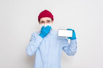 Fototapeta na wymiar Shocked courier in a medical mask shows phone, portrait, copy space, white background