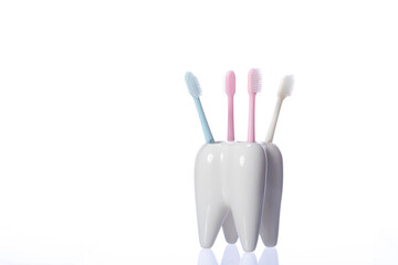 Family toothbrushes in ceramic tooth-shaped holder isolated on white background. Oral care, personal hygiene, healthy oral cavity, dental equipment, morning routine. Copy space, dental poster concept