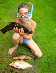 Boy diver with big fish on the green coast. 