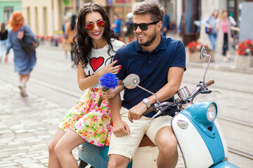 young beautiful hipster couple riding on motorbike city street, summer europe vacation, traveling, romance, smiling, happy, having fun, sunglasses, stylish outfit, together in love, adventures, date