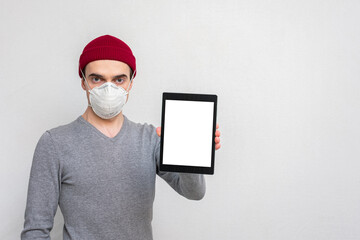 Person in a medical mask shows a tablet computer, portrait, copy space