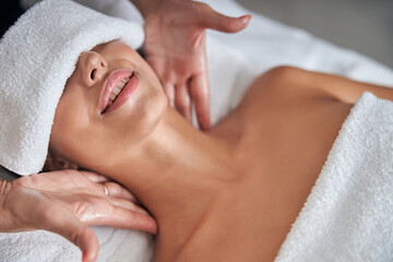 Masseur hands massaging young woman neck in spa salon