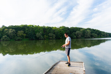 Man fishing on the pier. Fishing on the river on a sunny day. Autumn predator fishing