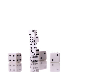 Stack of five white dice and Scattered dice of different sizes reflected in table surface isolated on white background copy space