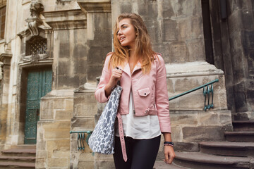 young beautiful woman traveling in europe, summer vacation, leather pink jacket, glam rock style, flirty, city street style