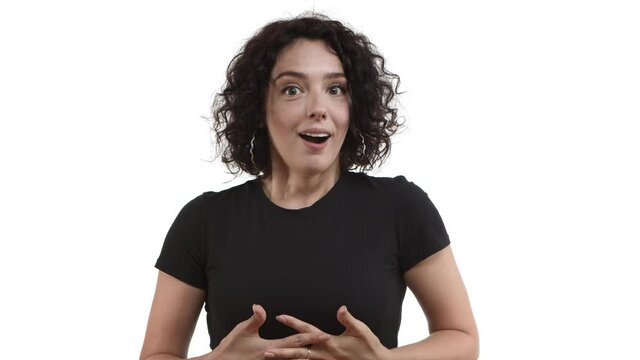 Close-up of pretty young woman with short curly hair, wearing black t-shirt, gasping surprised and then smiling, feeling thankful for something, standing over white background