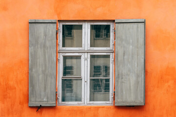 Old wooden window shutters of an european house with orange painted facade