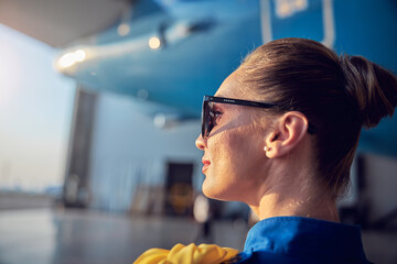 Happy smiling woman flight attendant in blue uniform enjoying good weather while working in the...