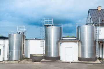Fototapeta premium Set of stainless steel metal dairy tanks, industry building