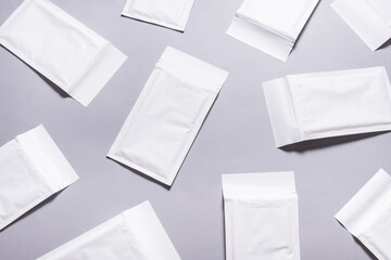 Lot of white paper bubble envelopes on grey background, textured background