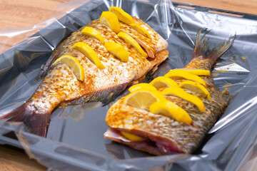 Raw fish with lemon and spices on baking tray