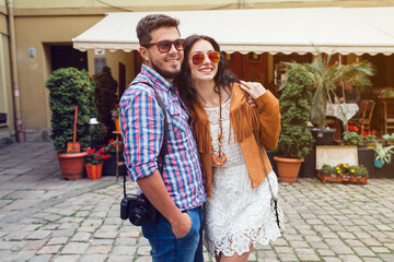 young man and woman in love traveling around europe, summer vacation, honey moon, having fun, suglasses, vintage style, smiling happy, embracing, photo camera