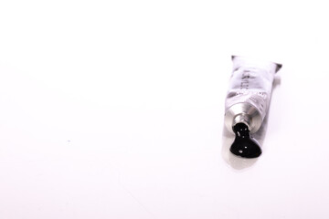 Squeezed black tube of acrylic paint isolated on white background. Smear of oil paint color on table. Art, artist workshop, drawing hobby, creative, design, black lives mater concept. Copy space