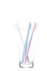 Three colorful plastic pastel shades Toothbrushes in glass isolated on white background. Love triangle concept. threesome concept. Brush your teeth every day