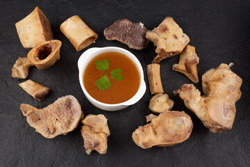 Fototapeta premium Homemade Beef Bone Broth in white bowl on a dark stone background. Bones contain collagen, which provides the body with amino acids, which are the building blocks of proteins