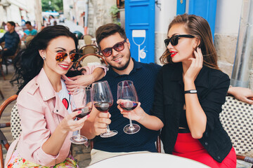 young hipster company of friends sitting in city street cafe, holding glasses, toasting, celebrating, drinking wine, sunglasses, summer vacation, party, having fun, smiling, happy, positive