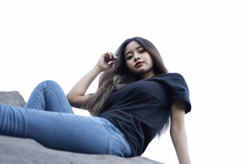 Fototapeta premium photographing a model of a girl sitting on a large rock wearing a black t-shirt and jeans. black t-shirt models for mockups and templates.