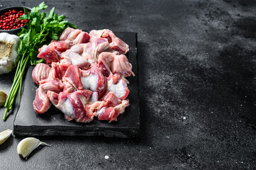 Raw uncooked chicken gizzards, stomach. Black background. Top view. Copy space