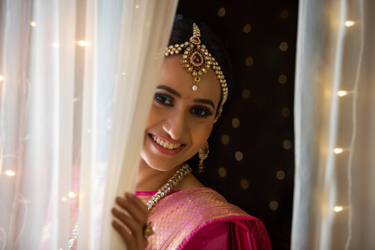 Woman in ethnic attire smiling thought the curtain	