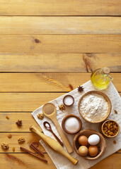 Ingredients for making homemade dough: flour, eggs, yeast, sugar, salt, oil, walnuts, raisins, cinnamon on wooden background. Empty space for the recipe. Festive cooking. Flat lay, copy space, mock up