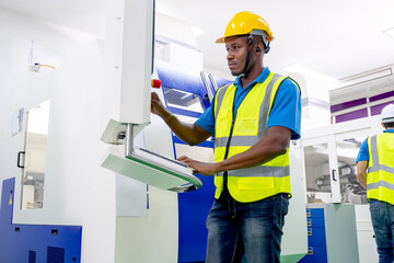 African American factory worker work with the machine in workplace area. Concept of good management system to support industrial business working.