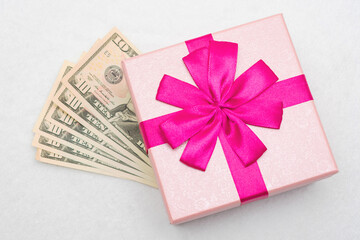 USA dollars and pink gift with ribbon, white background, top view