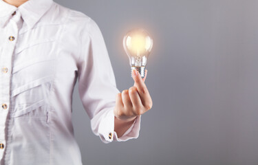 Woman hand holding a bulb. On a gray background.