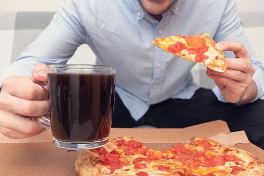 Man with a slice of pizza and glass of beer, man's hands, cropped image, closeup. Concept of junk food