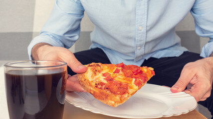 Obraz na płótnie Canvas Man takes a slice of pizza from a plate, man's hands, cropped image, closeup. Concept of junk food, 16:9