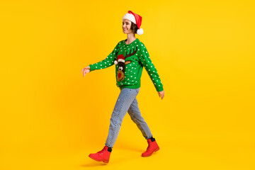 Full length profile side photo positive girl in santa claus headwear go walk copyspace x-mas christmas theme party wear deer decor sweater jeans boots isolated bright shine color background