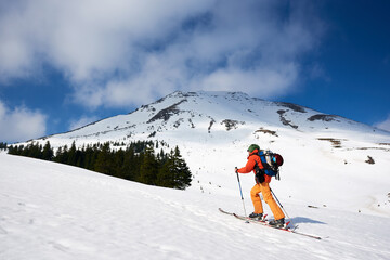 Ski touring man reaching the top in the spectacularly snowy mountains at sunny day. Snow and winter...