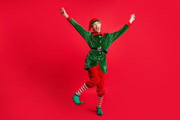 Full size photo of crazy elf dancing with raised fists wear costume headwear isolated on bright...