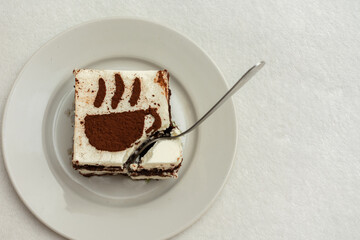 Piece of chocolate cake with a teaspoon, drawing in the form of a Cup of coffee, top view, close up