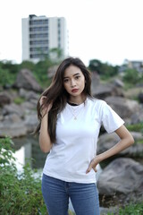 Gadis pirang bergaya memakai kaos putih dengan pemandangan bebatuan alam dan langit cerah. model kaos wanita untuk mockup dan template.