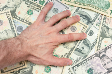 Greedy man with scattered dollars, a man's hand, close-up