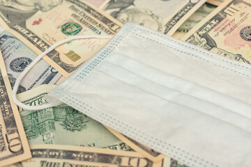 USA dollar bills and medical mask, top view, closeup